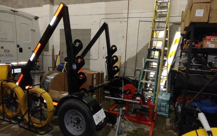 The cable reel trailer in the shop, standing beside racked rod-and-rope reels.